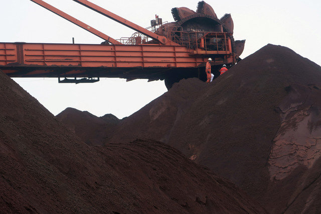 FOTO DE ARCHIVO: Se ven trabajadores sobre un montón de mineral de hierro mientras una máquina mezcla el mineral en el Puerto de Dalian, provincia de Liaoning, China, el 21 de septiembre de 2018. Foto tomada el 21 de septiembre de 2018. REUTERS/Muyu Xu/File Photo