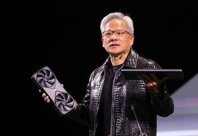 Nvidiaのジェンセン・フアンCEOが、ラスベガス(ネバダ州、米国)で開催された年次消費者向け電子機器見本市CES 2025で基調講演を行う際に、新型Nvidia GeForce RTX 5090グラフィックスカードとRTX 5070ノートパソコンを手に持っている。2025年1月6日。REUTERS/Steve Marcus