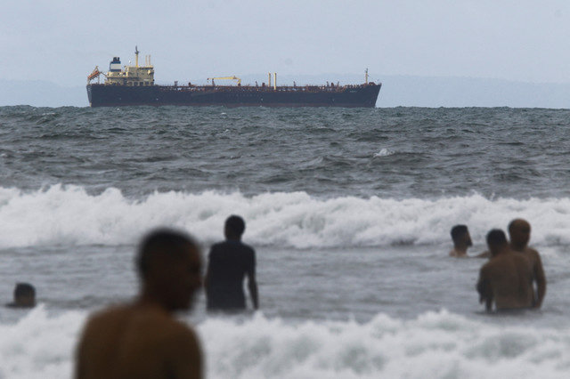 Pessoas aproveitam o mar perto do navio-tanque Evana, de bandeira das Comores, usado para transportar petróleo entre portos domésticos na Venezuela, perto do terminal El Palito, em Puerto Cabello, Venezuela, em 29 de dezembro de 2025. REUTERS/Juan Carlos Hernandez