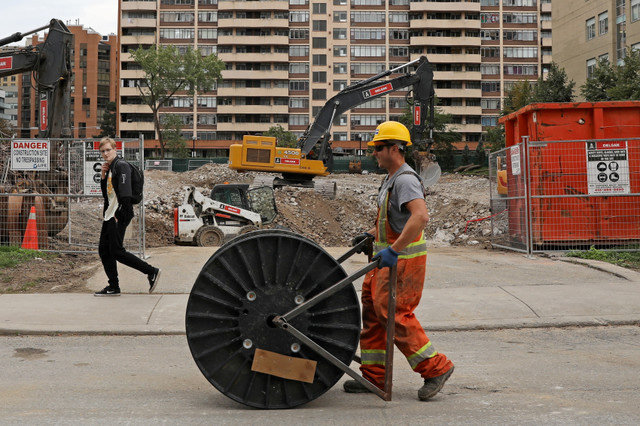A construction worker walks by a condominium site carrying a roll of cable in Toronto, Ontario, Canada, on October 8, 2021. REUTERS/Chris Helgren