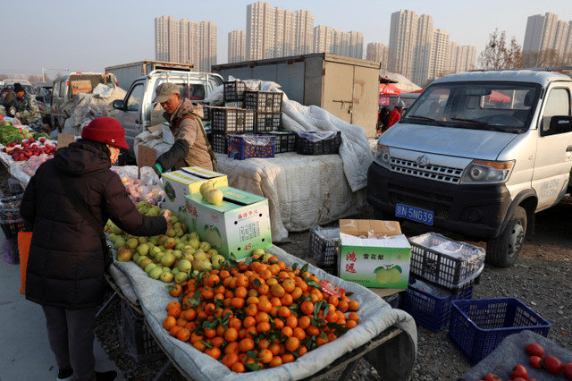 FILE PHOTO: A fruit vendor attends to a customer at an outdoor market in Beijing, China, January 12, 2024. REUTERS/Florence Lo/File Photo