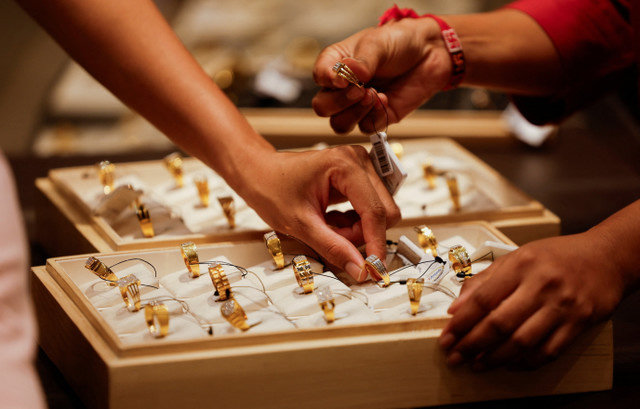 A salesperson shows a gold ring to customers at a jewellery showroom in Ahmedabad, India, October 8, 2025. REUTERS/Amit Dave