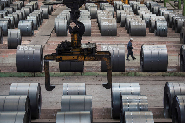 A worker walks past steel rolls at the Chongqing Iron and Steel plant in Changshou, Chongqing, China, on August 6, 2018. REUTERS/Damir Sagolj