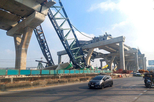 Cars drive next to a collapsed crane that crushed two vehicles during construction of an elevated highway in Samut Sakhon province, Thailand, January 15, 2026. Thai Rescue Worker Association/ Handout via REUTERS