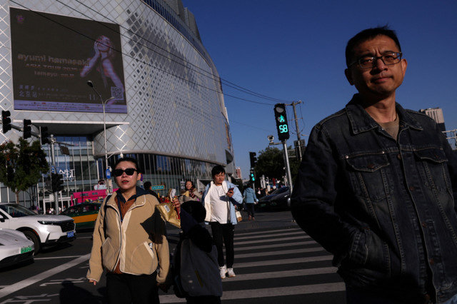 أشخاص يسيرون في شارع بالقرب من مركز تسوق في بكين، الصين، في 19 أكتوبر 2025. REUTERS/Tingshu Wang