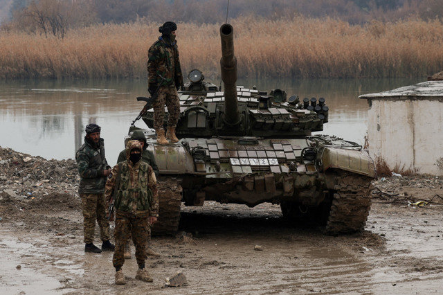 Personal militar permanece en el cruce que conecta las dos orillas del río Éufrates, mientras otros intentan cruzar al otro lado después de que las Fuerzas Democráticas Sirias (SDF) se retiraran de la provincia de Deir al-Zor y el ejército sirio tomara el control total de la zona, en Deir al-Zor, Siria, 18 de enero de 2026. REUTERS/Khalil Ashawi