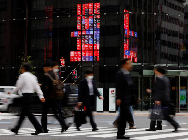2023年10月31日,日本东京的一个商业区,行人走过显示各公司股价的电子显示屏。REUTERS/Kim Kyung-Hoon