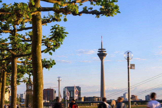 People walk at the promenade by the river Rhine with the skyline including Rheinturm in the background in Duesseldorf, Germany, May 13, 2024. REUTERS/Jana Rodenbusch