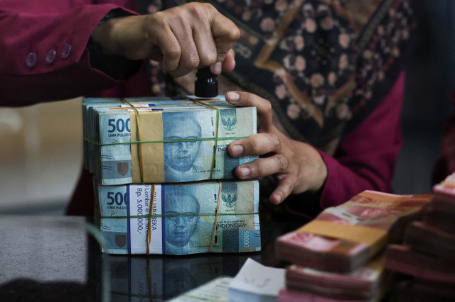 พนักงานเตรียมธนบัตรเงินรูเปียห์ที่จุดแลกเปลี่ยนเงินตราในกรุงจาการ์ตา ประเทศอินโดนีเซีย เมื่อวันที่ 9 เมษายน 2025 ภาพถ่ายผ่านกระจก REUTERS/Willy Kurniawan