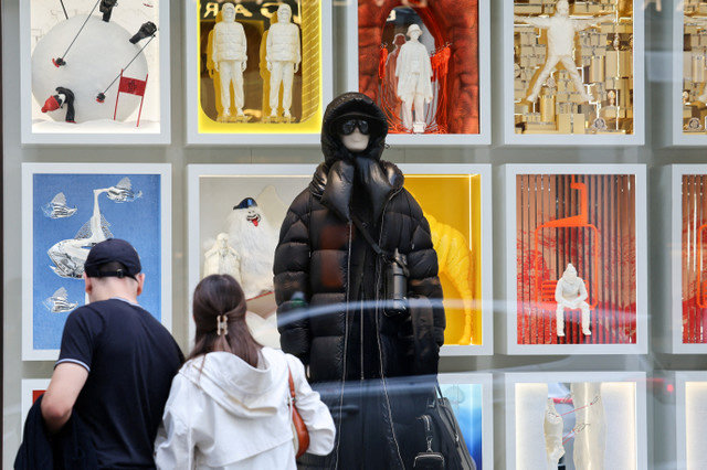 FOTO DE ARQUIVO: Pessoas observam a vitrine de uma loja da Moncler em Milão, Itália, em 24 de setembro de 2025. REUTERS/Yara Nardi/File Photo