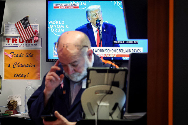 A trader works on the floor of the New York Stock Exchange (NYSE) as a screen displays U.S. President Donald Trump speaking at the World Economic Forum (WEF) in Davos, Switzerland, on January 21, 2026. REUTERS/Brendan McDermid