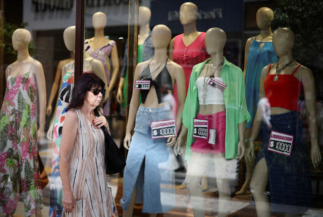 Uma mulher passa por uma loja de roupas em Buenos Aires, Argentina, em 4 de janeiro de 2024, enquanto o país enfrenta uma inflação anual que se aproxima de 200%. REUTERS/Agustin Marcarian