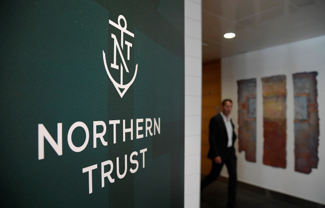 An employee walks past a company logo at Northern Trust offices in London, Britain, on August 1, 2019. Picture taken August 1, 2019. REUTERS/Toby Melville