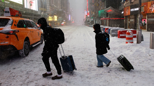 Personas caminan con equipaje durante una nevada en Times Square mientras una gran tormenta invernal se extiende por una amplia zona de los Estados Unidos, en la ciudad de Nueva York, EE. UU., el 25 de enero de 2026. REUTERS/Eduardo Munoz