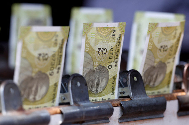 Notas de vinte rupias indianas são exibidas em uma banca de câmbio na beira da estrada em Nova Deli, Índia, em 24 de maio de 2024. REUTERS/Priyanshu Singh