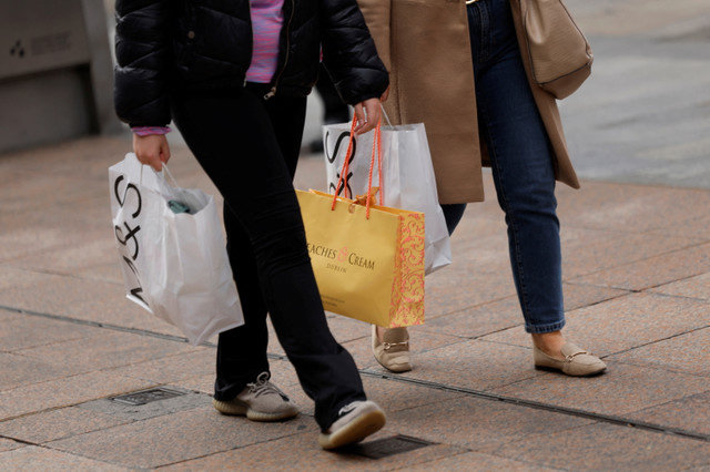 People walk holding shopping bags on a retail street, in Dublin, Ireland September 29, 2025. REUTERS/Clodagh Kilcoyne