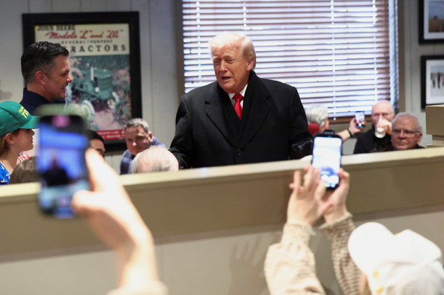 People hold their phones up as U.S. President Donald Trump interacts with diners at Machine Shed restaurant in Urbandale, Iowa, on January 27, 2026. REUTERS/Kevin Lamarque