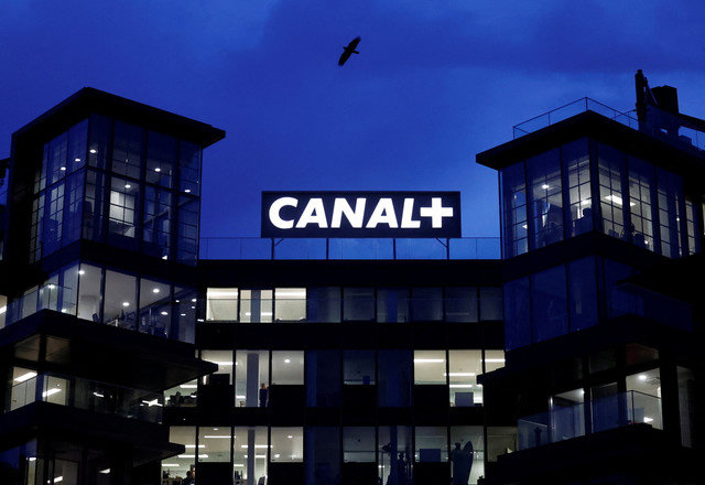 Logos of French TV channel Canal+ are reflected in a puddle in front of the Canal One headquarters of the Canal+ Group in Issy-Les-Moulineaux near Paris, France, February 20, 2025. REUTERS/Abdul Saboor