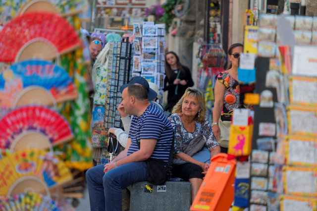 Tourists sit in front of a gift shop in the inner city of Palermo, Italy, May 14, 2025. REUTERS/Igor Petyx