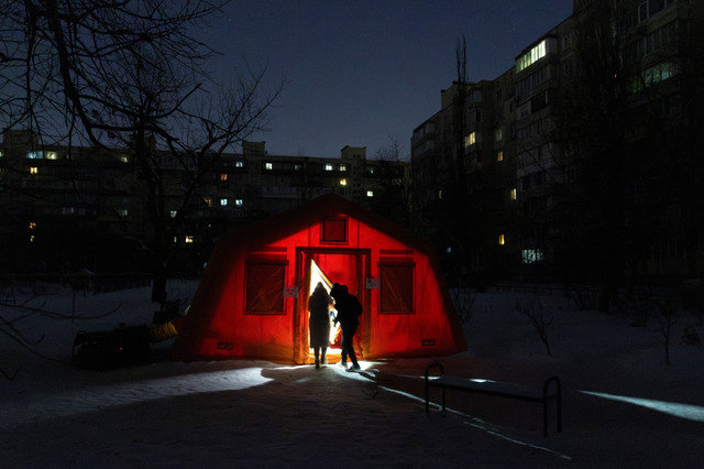 Personas entran en una carpa proporcionada por los servicios de emergencia para residentes cuyos apartamentos se quedaron sin calefacción durante temperaturas bajo cero, en medio del ataque de Rusia a Ucrania, en una noche de invierno en Kiev, Ucrania, el 17 de enero de 2026. REUTERS/Thomas Peter