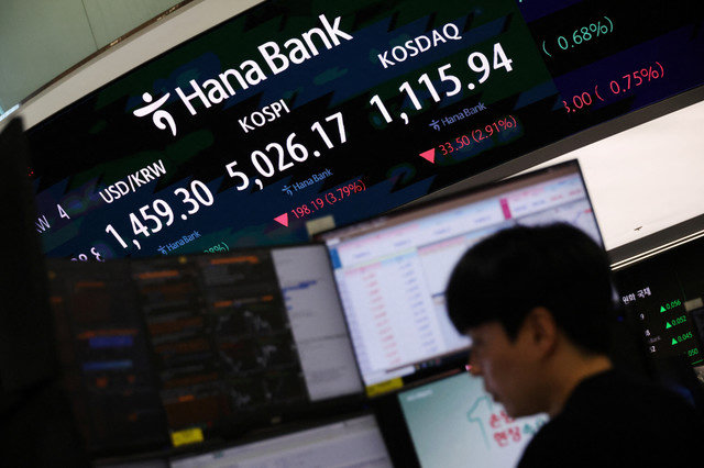 2026年2月2日,在韩国首尔的一家银行交易室内,一名外汇交易员正在工作,电子显示屏上显示着韩国综合股价指数(KOSPI)、美元兑韩元汇率和韩国证券交易商协会自动报价指数(KOSDAQ)。 REUTERS/Kim Hong-Ji