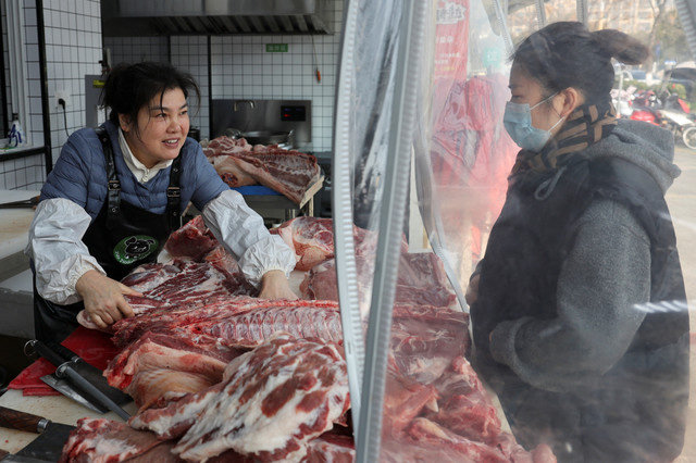 Um funcionário atende um cliente que compra carne de porco em uma loja de porco preto em Taizhou, província de Jiangsu, China, em 16 de janeiro de 2026. REUTERS/Go Nakamura