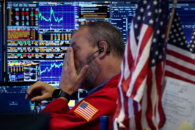 FILE PHOTO: A trader works inside a booth on the floor at the New York Stock Exchange (NYSE) in New York City, U.S., November 21, 2025. REUTERS/Brendan McDermid/File Photo