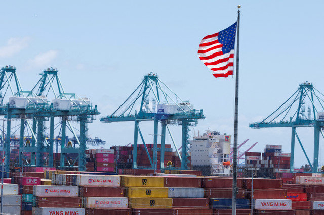 FILE PHOTO: An American flag flutters over a ship and shipping containers at the Port of Los Angeles, in San Pedro, California, U.S., May 13, 2025. REUTERS/Mike Blake/File Photo