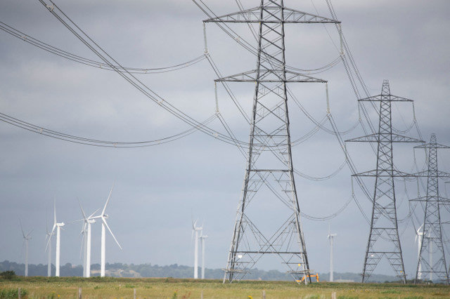Onshore wind turbines at Little Cheyne Court Wind Farm operate beside electricity pylons in Dungeness, Britain, July 10, 2024. REUTERS/Chris J. Ratcliffe