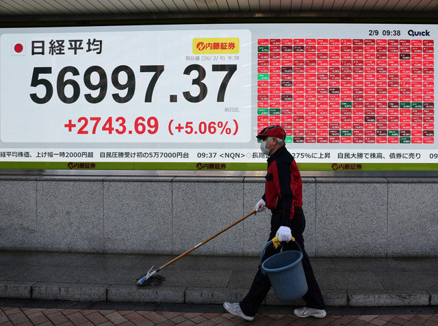 Un trabajador limpia el suelo frente a un panel electrónico que muestra el promedio de acciones Nikkei frente a una correduría en Tokio, Japón, el 9 de febrero de 2026. REUTERS/Kim Kyung-Hoon