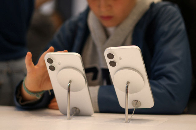 2024年10月6日、イギリスのロンドンにある店舗で、展示されているAppleのiPhoneスマートフォンを使用する子供。REUTERS/Hollie Adams
