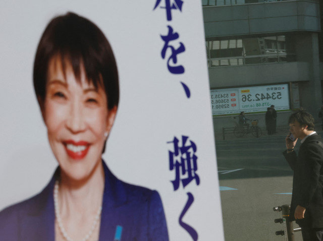An election poster featuring Japanese Prime Minister Sanae Takaichi is displayed on a shop window reflecting a Nikkei share average board ahead of the February 8 snap election in Tokyo, Japan, February 6, 2026. REUTERS/Kim Kyung-Hoon