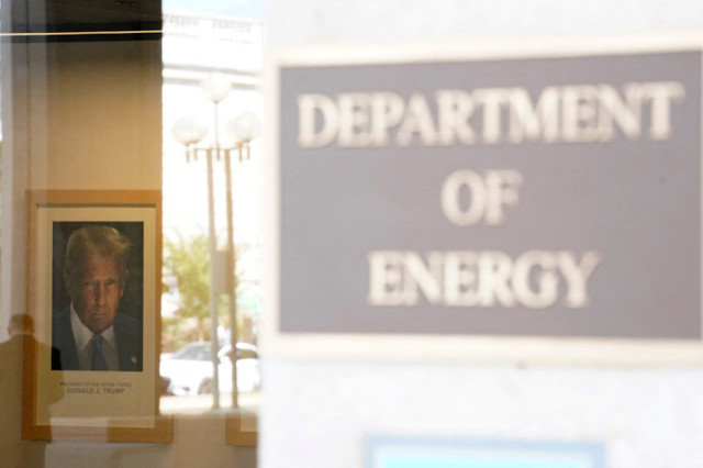 Uma pessoa reflete-se na janela do Departamento de Energia dos EUA, com o retrato oficial do presidente Donald Trump na parede, após uma paralisação parcial do governo em Washington, D.C., em 2 de outubro de 2025. REUTERS/Nathan Howard/File Photo