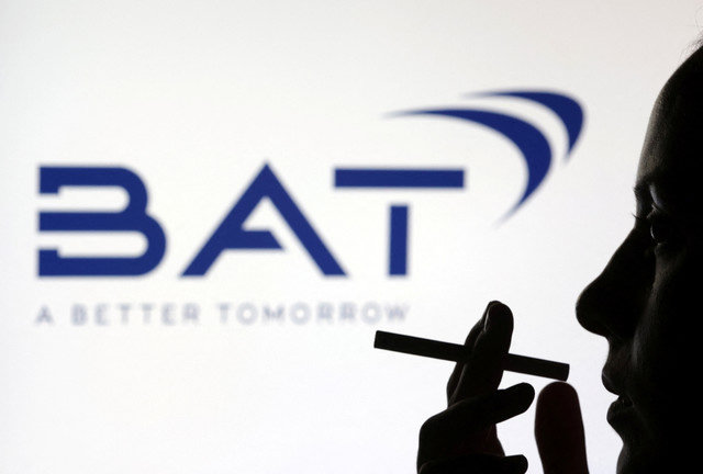 A woman poses with a cigarette in front of the British American Tobacco (BAT) logo in this illustration taken on July 26, 2022. REUTERS/Dado Ruvic/Illustration