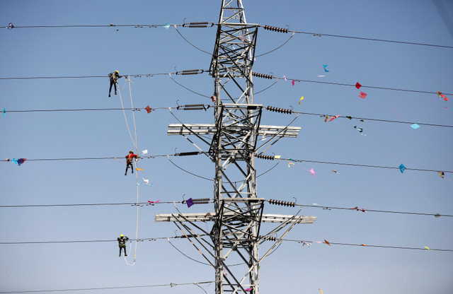 Workers of Torrent Power Limited remove kites and thread tangled in electric power cables following the kite flying season in Ahmedabad, India, on January 16, 2020. REUTERS/Amit Dave/File Photo