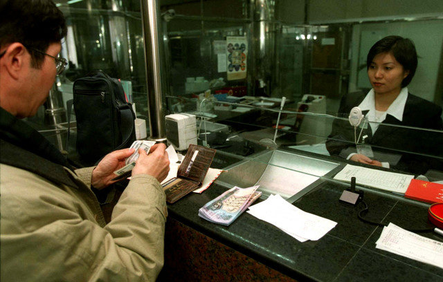 Un hombre realiza una transacción en un banco de Pekín el 7 de diciembre, mientras el Banco Central de China reduce las tasas de interés de depósitos y préstamos en un promedio de 0,5 puntos porcentuales para estimular la economía y alcanzar el objetivo de crecimiento anual del 8,0 por ciento. RW/JO//File Photo