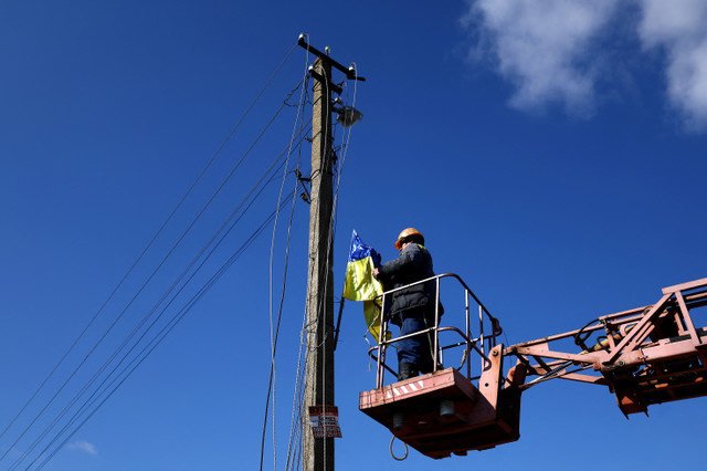 A worker repairs the power cord of a pylon in Pravdyne, Kherson region, Ukraine, February 23, 2023. REUTERS/Lisi Niesner/File Photo
