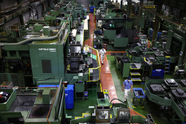 Workers walk between precision-machining machines for automotive parts inside a factory at Kyowa Industrial Co. in Takasaki, Gunma Prefecture, Japan April 11, 2025. REUTERS/Issei Kato