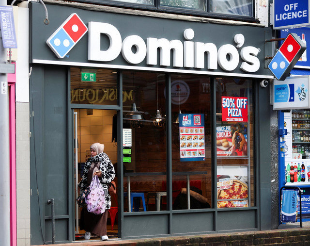 A woman leaves a branch of the Domino's Pizza franchise in London, Britain, December 5, 2025. REUTERS/Hiba Kola