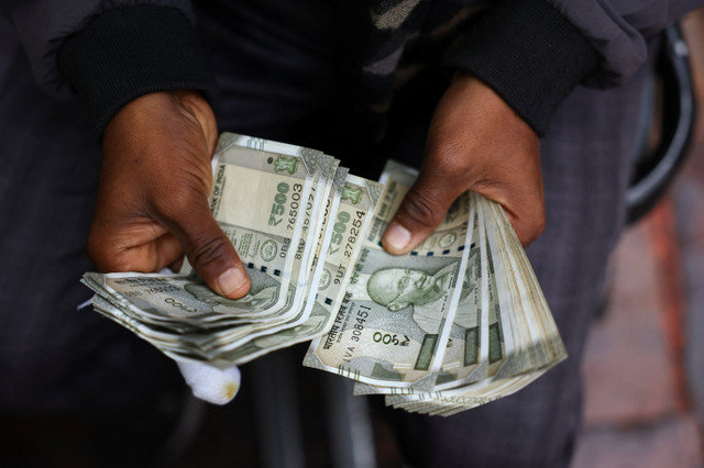 A man counts Indian currency notes at a roadside currency exchange stall in the old quarters of Delhi, India, February 2, 2026. REUTERS/Anushree Fadnavis