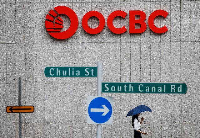 ผู้คนเดินผ่านป้ายธนาคาร OCBC ในสิงคโปร์เมื่อวันที่ 11 กรกฎาคม 2023 REUTERS/Edgar Su