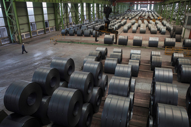 A worker walks past steel rolls at the Chongqing Iron and Steel plant in Changshou, Chongqing, China, on August 6, 2018. REUTERS/Damir Sagolj/ File Photo