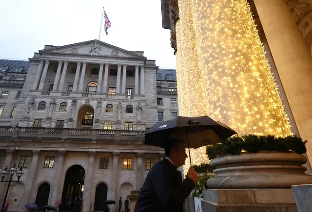Uma pessoa se protege da chuva enquanto caminha perto do edifício do Banco da Inglaterra no dia em que o Comitê de Política Monetária reduziu as taxas de juros, em Londres, Grã-Bretanha, 18 de dezembro de 2025. REUTERS/Toby Melville