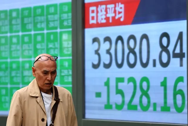 An individual walks by a digital board showing the Nikkei stock index in Tokyo, Japan, in an image from April 2025. REUTERS/Kim Kyung-Hoon