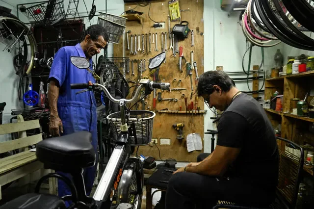 Os mecânicos Israel Garcia e Alain Tundidor reparam uma bicicleta elétrica em sua oficina em Havana, Cuba, 24 de fevereiro de 2026. REUTERS/Norlys Perez