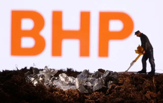 Uma pequena figura de brinquedo e uma imitação de mineral são vistas em frente ao logotipo da BHP nesta ilustração de 19 de novembro de 2021. REUTERS/Dado Ruvic/Illustration