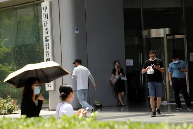 2021年7月9日、中国・北京の金融街にある中国証券監督管理委員会(CSRC)の看板の前を通り過ぎる人々。REUTERS/Tingshu Wang
