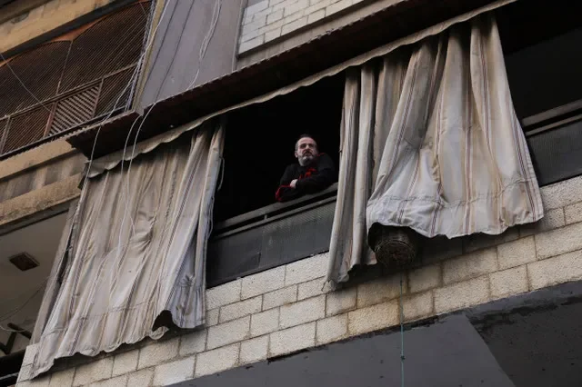 一名男子从黎巴嫩贝鲁特市中心受损建筑的阳台向外张望。REUTERS/Emilie Madi