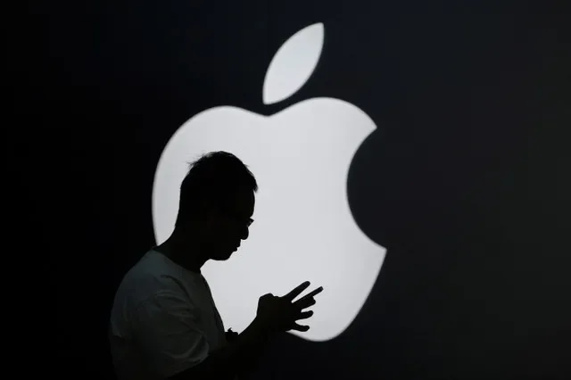 2023年9月13日、中国・上海のアップルストアの外で、ロゴの近くでスマートフォンをチェックする男性。REUTERS/Aly Song