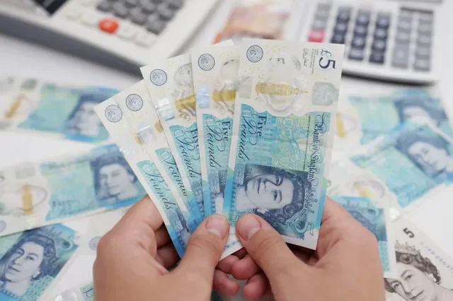 A person displays a collection of British Pound notes in this illustrative photo from May 2022. REUTERS/Dado Ruvic/Illustration